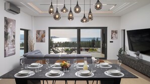 Un coin repas avec une table dressée pour six personnes, un canapé et une vue sur l’extérieur.