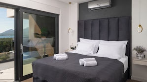 Une chambre moderne avec un grand lit, une porte-fenêtre coulissante donnant sur un balcon et une vue sur une montagne.