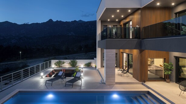 Un bâtiment moderne doté d’une piscine, d’un espace extérieur aménagé et offrant une vue sur les montagnes.