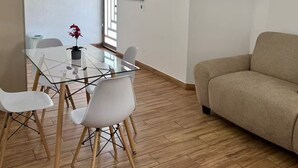 A modern living room with a flat-screen TV, a sofa, and a glass dining table with chairs. - Very Central | Tec Mty | Hosp Angeles | Invoicing (Torreón)