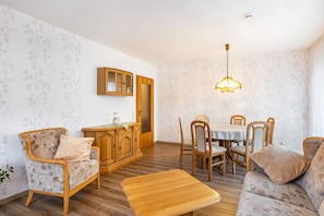 Un espace repas comprenant une table en bois, des chaises, un banc et un buffet.