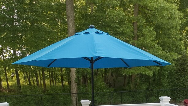 A deck with a blue outdoor sofa and a matching ottoman, a blue umbrella, and a white railing. - Private 4-Bedroom Oasis Near the World Cup Action—Only 9 Miles from Foxboro! (South Easton)