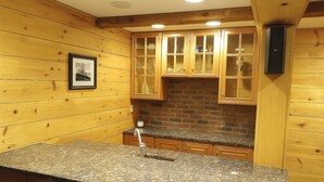 A kitchen with wooden walls, granite countertops, and a brick backsplash. - Private 4-Bedroom Oasis Near the World Cup Action—Only 9 Miles from Foxboro! (South Easton)