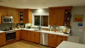 A modern kitchen with wooden cabinets, stainless steel appliances, and a marble countertop. - Private 4-Bedroom Oasis Near the World Cup Action—Only 9 Miles from Foxboro! (South Easton)