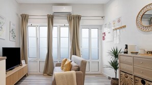 Un salon moderne avec un canapé, un téléviseur et une plante.