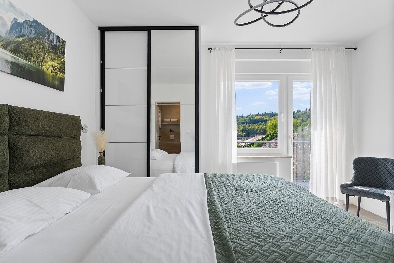 Un dormitorio con una cama grande, vistas a un paisaje montañoso, un armario y una silla.