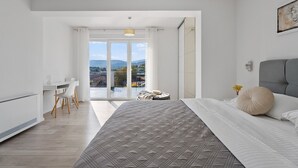 A modern bedroom with a large bed, a desk, and a view of the outdoors. - Villa Gloria: Stylish 5-Bedroom Retreat with Private Pool and Stunning Valley Views (Zmijavci)