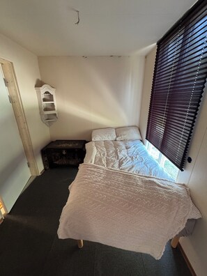 A bedroom with a bed, a chest of drawers, a window with blinds, and a door. - Cozy 6 Bedroom Holiday House in Oslo's Countryside (Oslo)