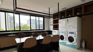 Une cuisine moderne avec un coin repas, de grandes fenêtres et des lave-linge encastrés.