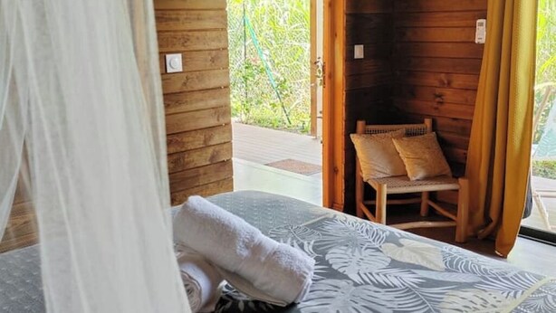Une pièce de cabane en bois comprenant un lit, une chaise et donnant sur un paysage verdoyant.