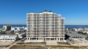 A high-rise hotel with multiple balconies, located near a beach and the sea.