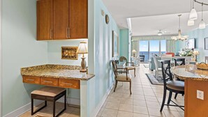 A kitchen with wooden cabinets, a granite countertop, and a dining area with chairs and a table.