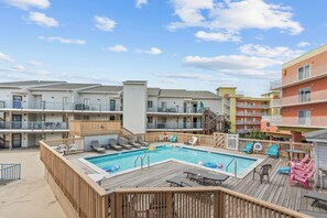 A pool area with lounge chairs and a wooden deck. - San Remo 108B (Ocean City)