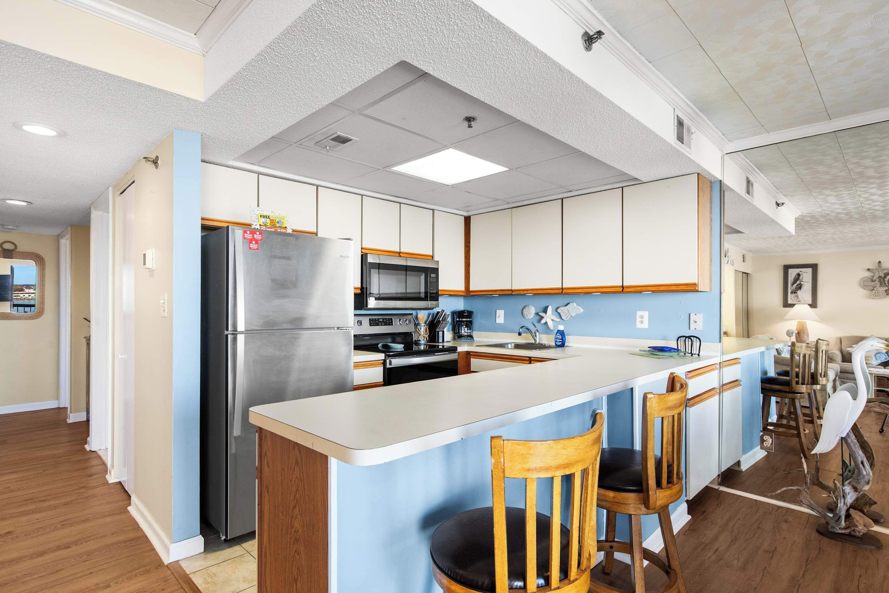 A modern kitchen with a central island, stainless steel appliances, and wooden chairs.