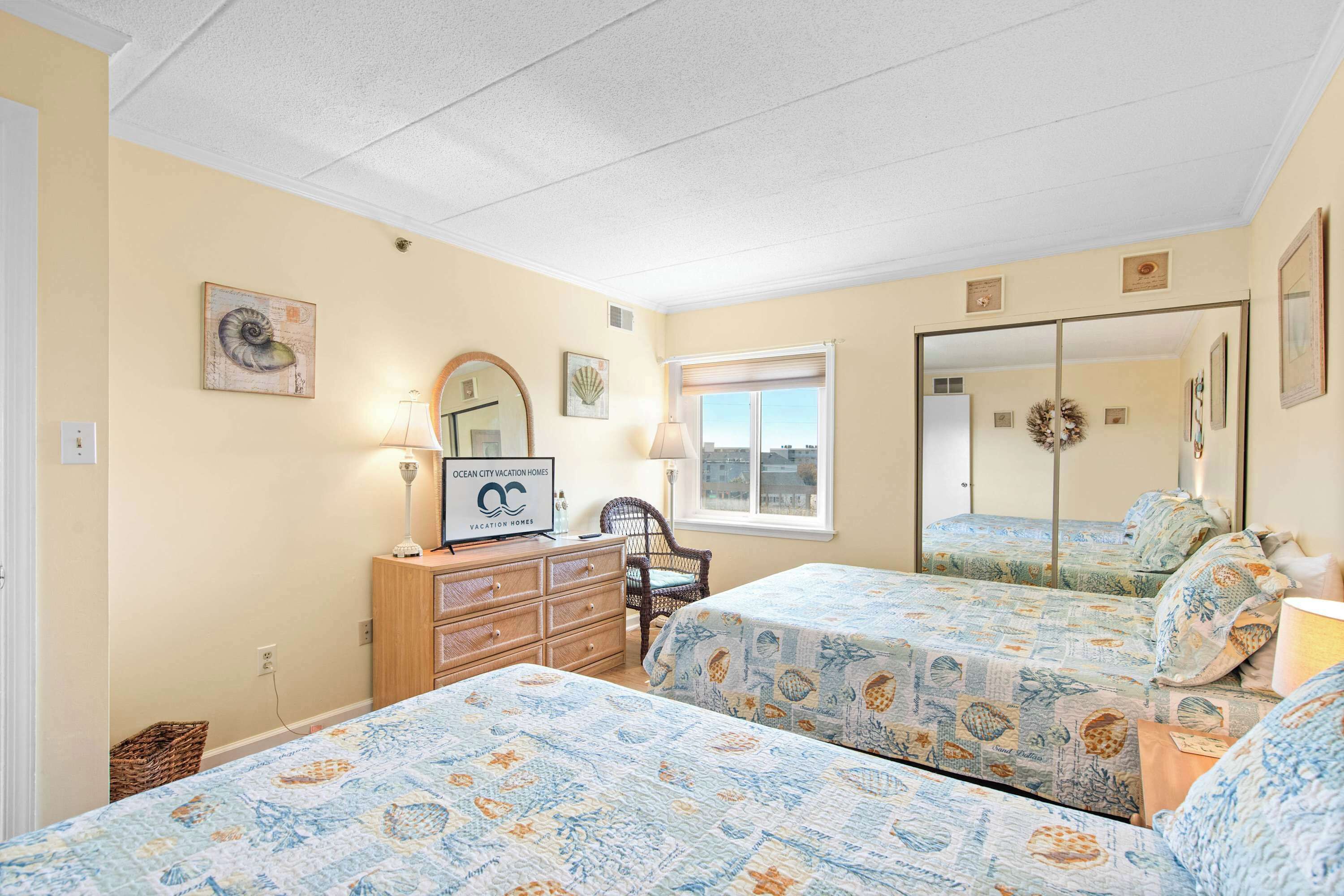 A bedroom with two beds, a dresser, a chair, and a window with a view.