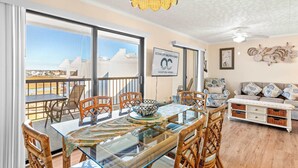 A dining area with a glass table, wicker chairs, and a view of the ocean. - Bay Princess 414 (Ocean City)