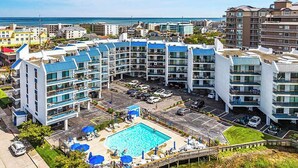 A hotel with a central pool, multiple balconies, and a view of the ocean. - Bay Princess 414 (Ocean City)