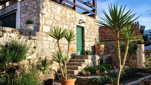 A stone building with a green door, potted plants, and a staircase leading to a balcony. - The Hidden Village Treasure - Villa Olka (Grabovac)