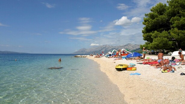 A beach with clear water, people sunbathing, and tents. - The Hidden Village Treasure - Villa Olka (Grabovac)