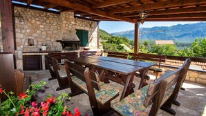 An outdoor patio with a stone wall, wooden table, and benches. - The Hidden Village Treasure - Villa Olka (Grabovac)