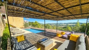 A covered outdoor seating area with a pool, wicker furniture, and a view of the countryside. - LE MANOIR DES HAUTS DE PIERREVAL: an exceptional stay in the heart of Périgord Noir (Coux et Bigaroque-Mouzens)