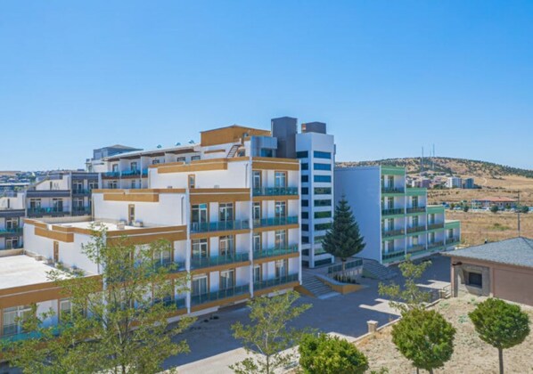 A multi-story hotel with balconies, a central courtyard, and a view of the surrounding landscape.