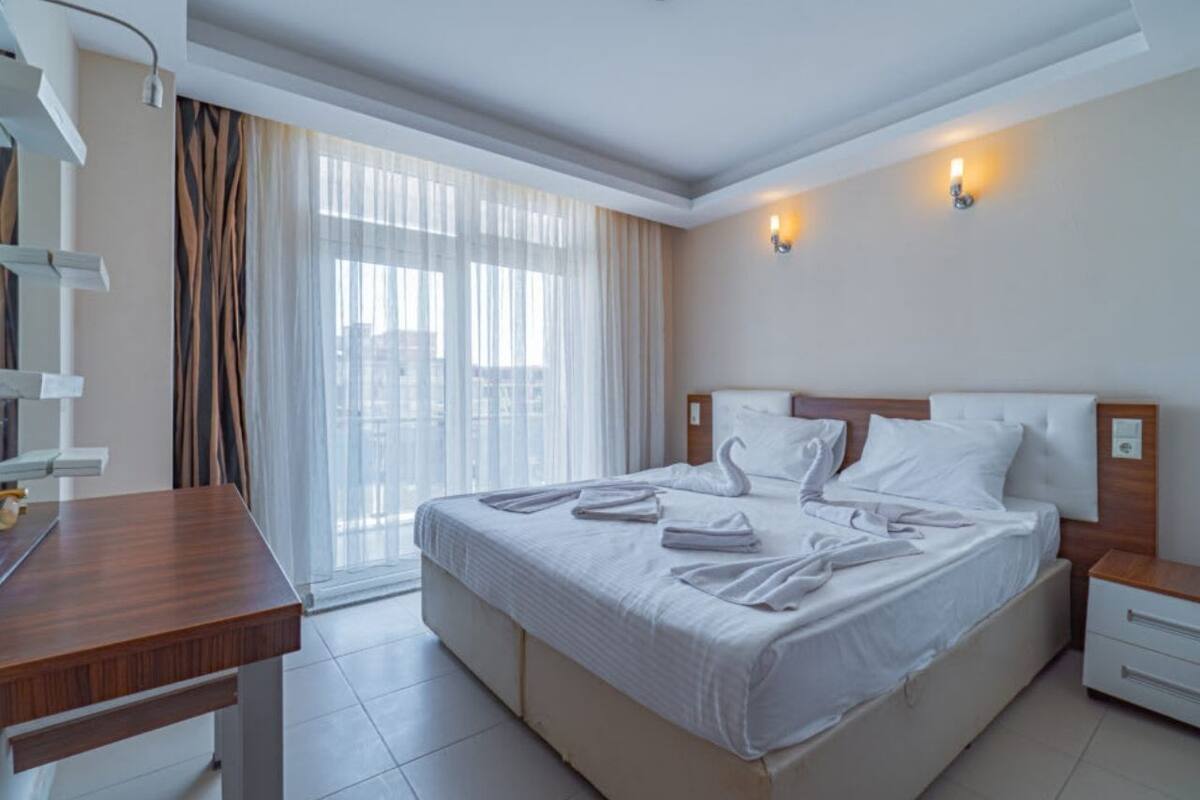 Een hotelkamer met een groot bed, een bureau en een raam met gordijnen.