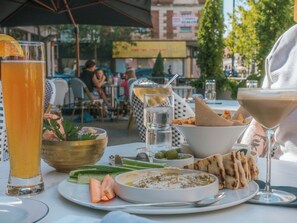 An outdoor dining area with a table set for a meal, including a bowl of salad, a plate of vegetables, and a glass of beer. - NEW Studio - Steps from Dining, Coffee & City Life (Cincinnati)