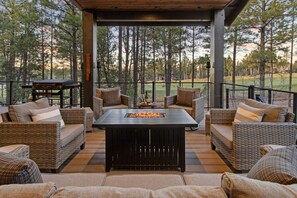 A covered outdoor seating area with wicker furniture and a central fire feature. - Sage Cabin | King Beds~Golf Course Views~Bunkroom (Show Low)