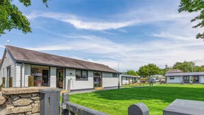 A row of single-story buildings with a stone wall and a wooden fence in the foreground. - Ash Cottages (Llanrwst)