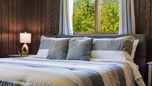 A bedroom with a bed, pillows, a nightstand, and a window with a view of trees. - Hiwassee Lake Lodge - Private Mtn-Top Retreat - Lake Views - Sleeps 13 (Murphy)