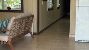 A hallway with a wicker sofa, a welcome mat, and a refrigerator. - Ocean Nest - 4-bedroom beach-front house in La Playa, Anasco Puerto Rico (La Playa)