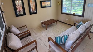 A room with a ceiling fan, a sofa, a bench, and framed artwork on the wall. - Ocean Nest - 4-bedroom beach-front house in La Playa, Anasco Puerto Rico (La Playa)