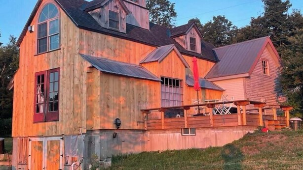 Una casa grande de madera con una torre destacada y varias ventanas.
