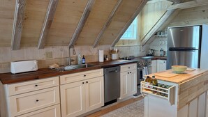 Una cocina moderna con vigas de madera, un refrigerador de acero inoxidable y una encimera de madera.