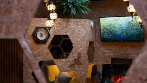 Uma sala de estar aconchegante com um pavão na parede, uma TV e uma lareira.