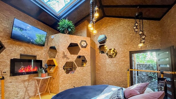 Um quarto moderno com claraboia, lareira, televisão e cama com almofadas decorativas.