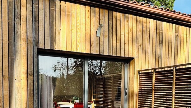 A wooden deck with a glass door leading to an outdoor dining area. - Bright little studio near Porto Vecchio🌴 (San-Gavino-di-Carbini)