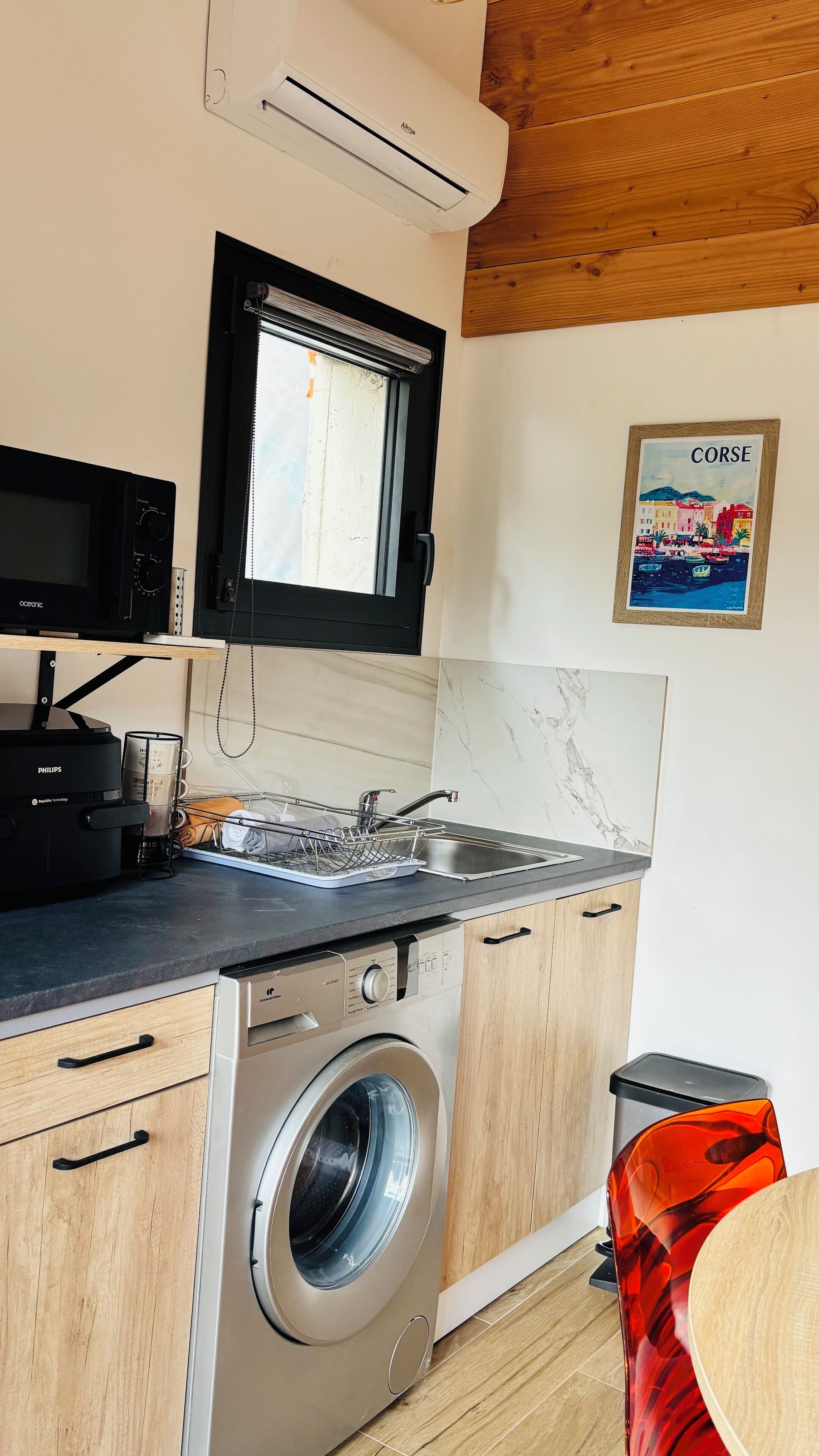 Una cocina compacta con lavadora, microondas y fregadero.