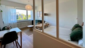 Een moderne hotelkamer met een groot bed, een bureau en een stoel. Een raam met uitzicht op gebouwen.