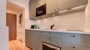 Een moderne keuken met grijze kastjes, een inbouwoven, een magnetron en een vaatwasser.