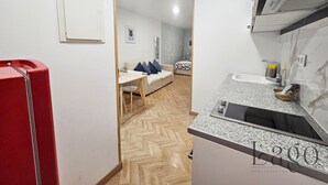 Une cuisine moderne avec un plan de travail en granit, un réfrigérateur rouge et un sol à motifs en chevrons.