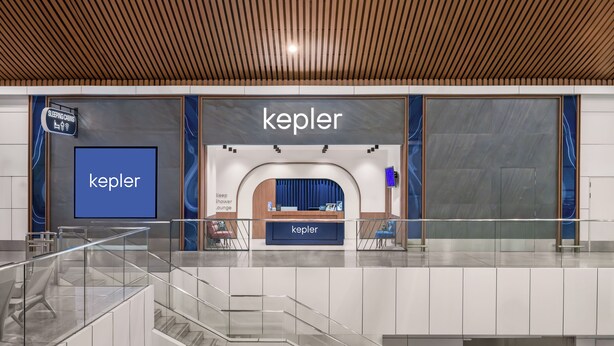 Een hotellobby met een receptiebalie, een bordje voor slaaphutten en een groot scherm waarop de hotelnaam 'Kepler' staat.