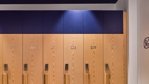 Een rij houten lockers met de nummers 205 tot en met 210, elk voorzien van een klein elektronisch slot.