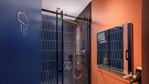 Een moderne badkamer met een douchecabine van glas, een regendouche en een inspirerende quote op de muur.