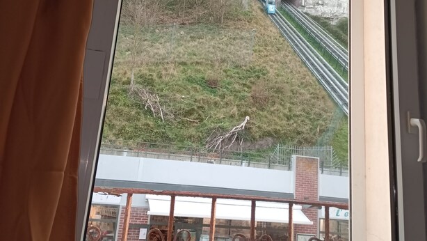 En vy genom ett fönster i en byggnad med en skylt som visar texten "TREPOT-TERRE BRASSE" och en trappa som leder till ett stenigt område.
