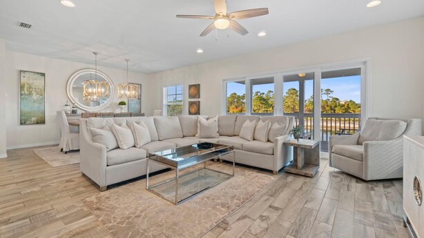 A spacious living room with a large sectional sofa, a glass coffee table, and a ceiling fan. - Gone Gulfing - Isle Be Chillin (Pensacola)