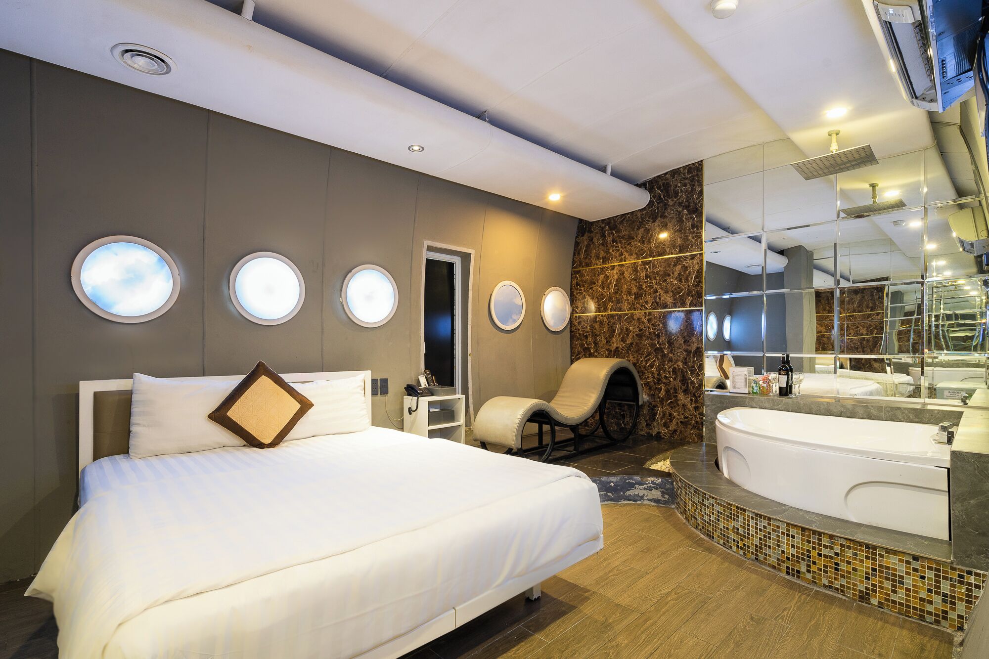 Une chambre d’hôtel moderne dotée d’un grand lit, d’un coin salon, d’une baignoire et d’un grand miroir.