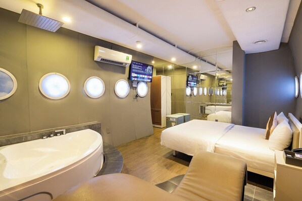Ein Hotelzimmer mit einer großen Badewanne, zwei Einzelbetten, einem Fernseher und einer Duschkabine.