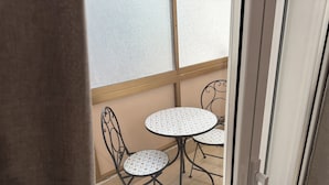 A view of a balcony with two round tables and chairs, a wooden floor, and a frosted glass window. - Bart165 Luxury Rooms (Palermo)